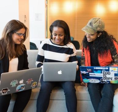 three women sit together with laptops 