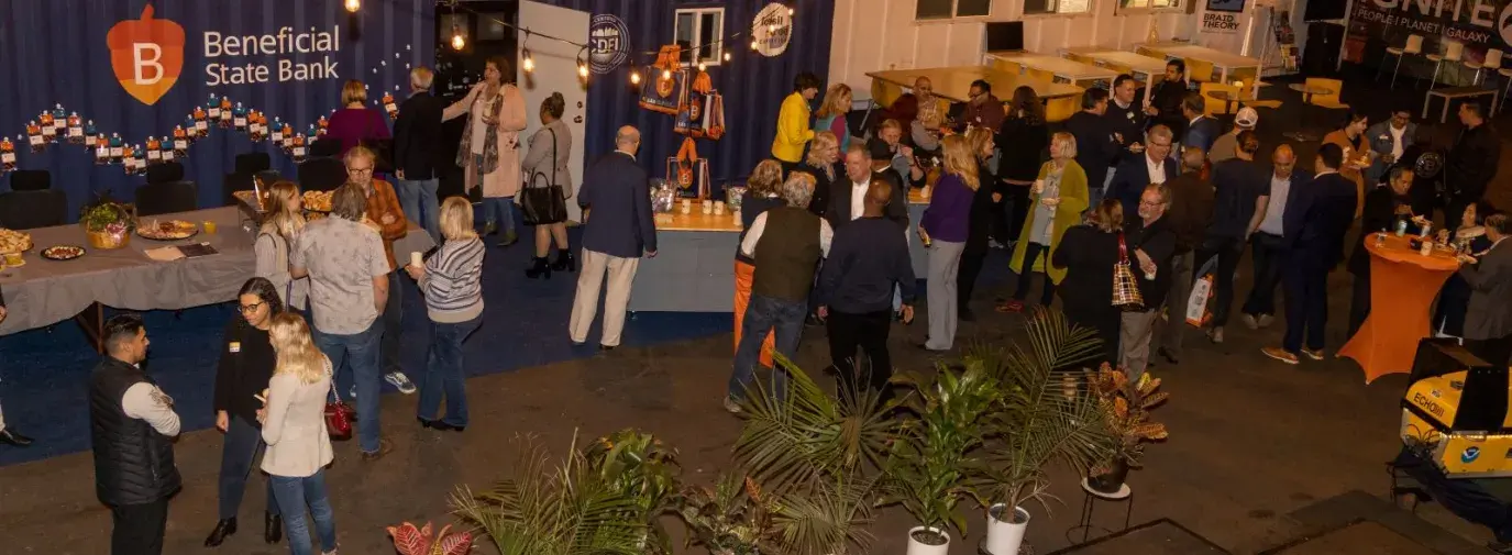 an aerial view of a grand opening at Beneficial State Bank. People are gathered in small groups, chatting. 
