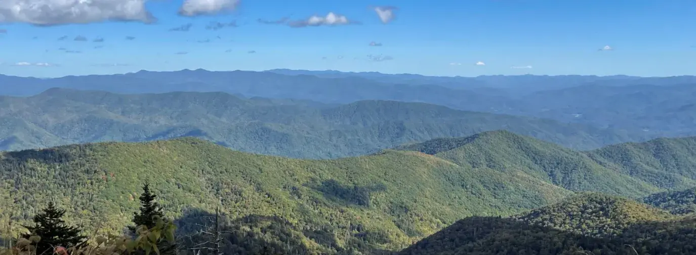 wide view of the blue ridge mountains. The closest mountains are green and turn blue the farther away they are. 