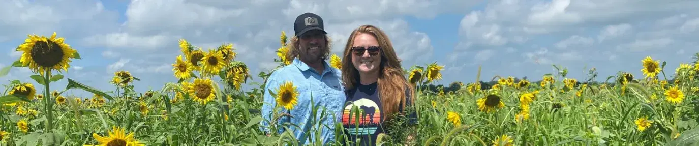 Nebraska farmers Brian and Liz James are standing in a field of sunflowers smiling at the camera.