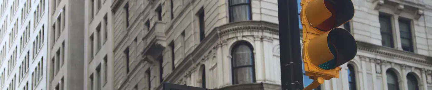 black street pole with street light and street sign saying "Wall St" against the backdrop of a tall, grey building with lots of windows, socially responsible investing must be a requirement