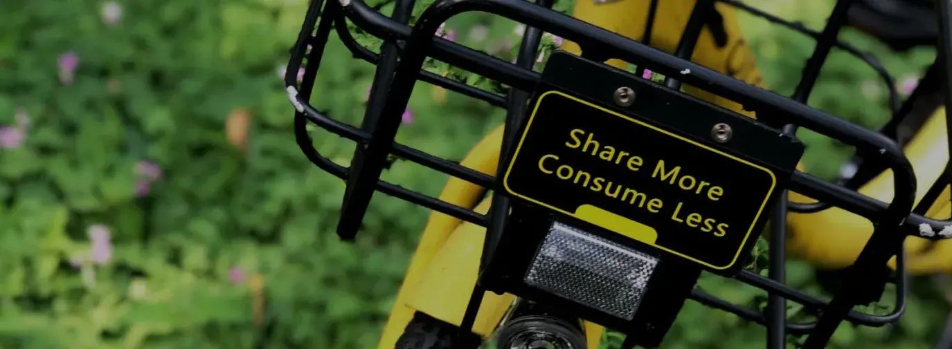 a yellow bike with a basket that reads "share more consume less"