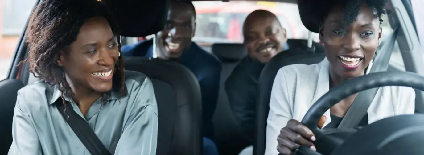 a group of friends take a ride together in the car and they are smiling at each other.
